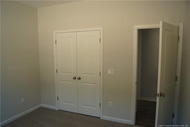 unfurnished bedroom with a closet, baseboards, and dark colored carpet