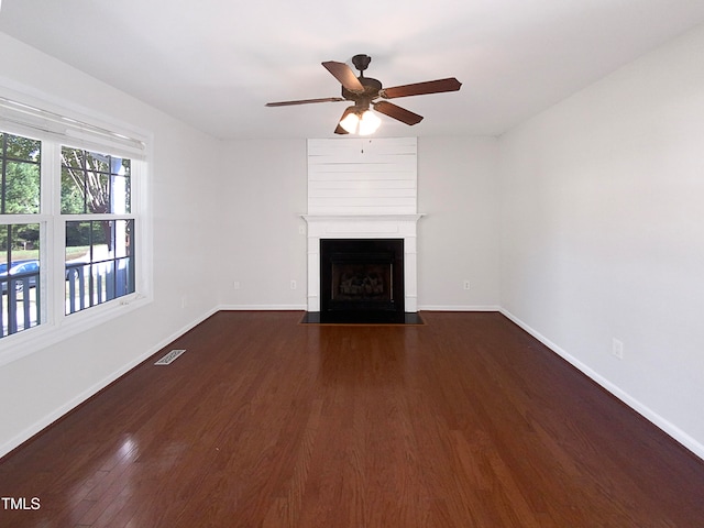 unfurnished living room featuring ceiling fan, a large fireplace, and dark hardwood / wood-style flooring