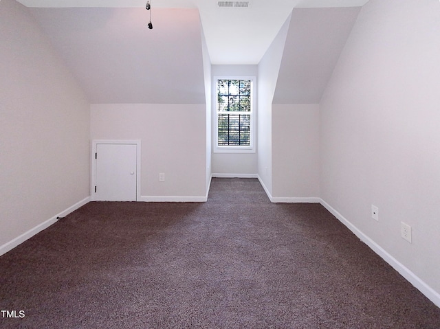 additional living space featuring lofted ceiling and dark colored carpet