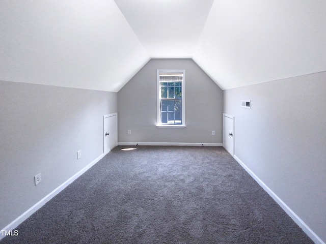 bonus room with vaulted ceiling and dark colored carpet