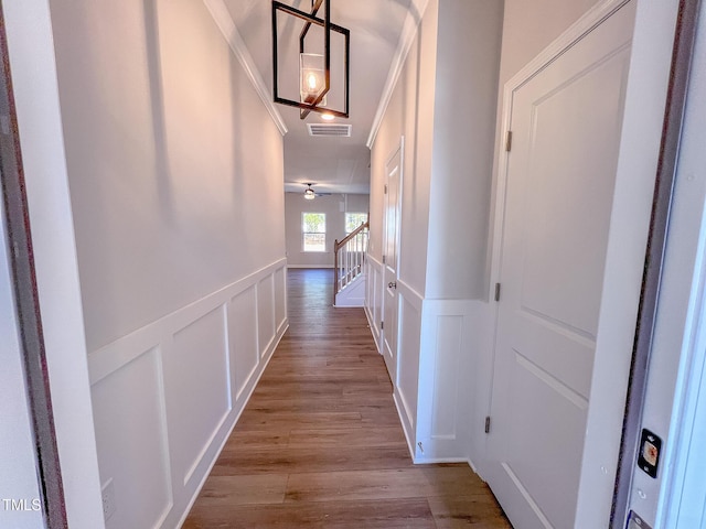 corridor with ornamental molding and light hardwood / wood-style floors