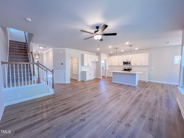 unfurnished living room with sink, light hardwood / wood-style flooring, and ceiling fan