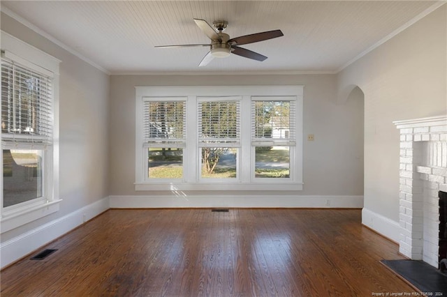 unfurnished room with crown molding, ceiling fan, a brick fireplace, and dark hardwood / wood-style flooring