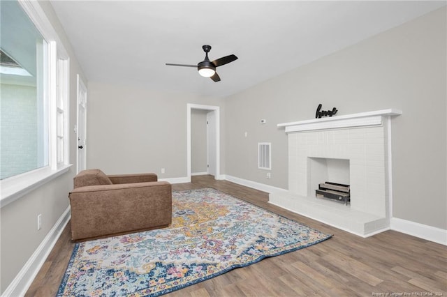 living room featuring a healthy amount of sunlight, ceiling fan, hardwood / wood-style flooring, and a fireplace