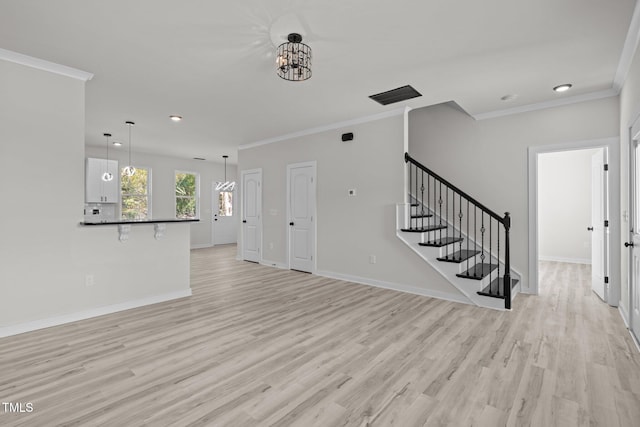 unfurnished living room featuring crown molding, a notable chandelier, and light wood-type flooring