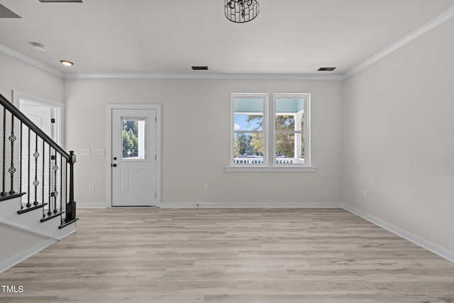 foyer entrance featuring ornamental molding, a healthy amount of sunlight, and light wood-type flooring