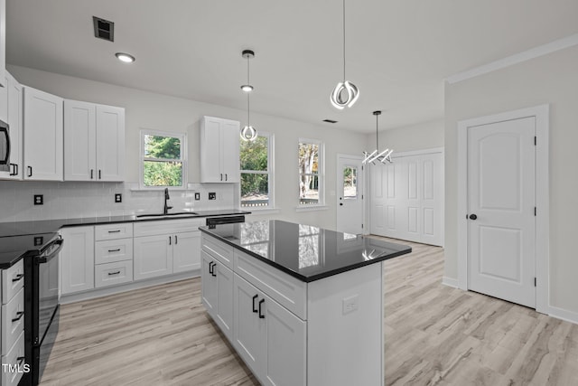 kitchen with a wealth of natural light, black electric range oven, and white cabinetry