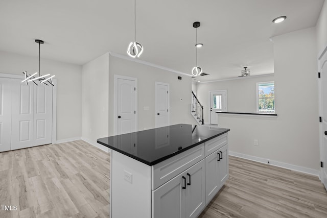 kitchen with a kitchen island, pendant lighting, an inviting chandelier, light wood-type flooring, and white cabinetry