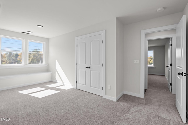 unfurnished bedroom featuring light colored carpet and a closet