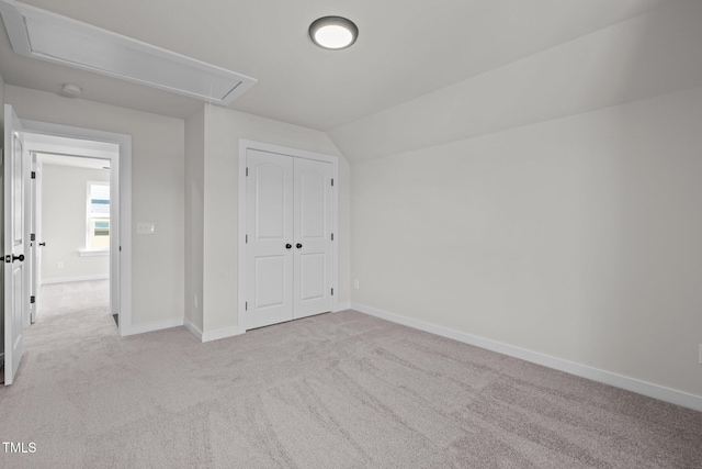 unfurnished bedroom with a closet, light colored carpet, and lofted ceiling