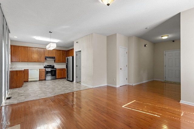 kitchen with appliances with stainless steel finishes, a textured ceiling, light wood-type flooring, sink, and decorative light fixtures