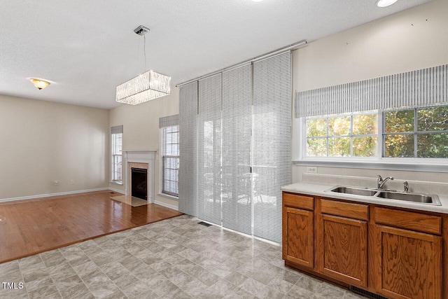 kitchen featuring light hardwood / wood-style flooring, hanging light fixtures, sink, an inviting chandelier, and a textured ceiling