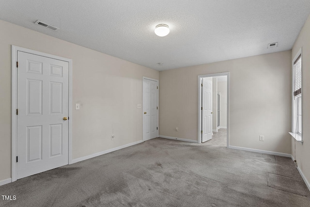 unfurnished room featuring a textured ceiling and light colored carpet