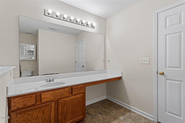 bathroom with vanity, a textured ceiling, and toilet