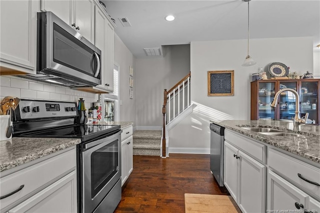 kitchen featuring appliances with stainless steel finishes, sink, dark hardwood / wood-style flooring, hanging light fixtures, and white cabinets