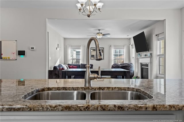 kitchen with sink, ceiling fan with notable chandelier, and a wealth of natural light