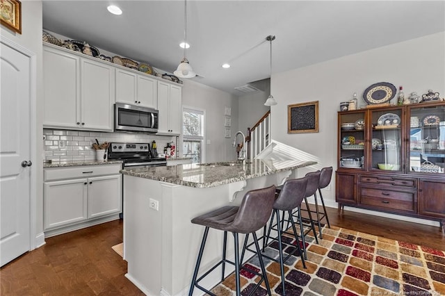 kitchen featuring white cabinets, a kitchen island with sink, sink, pendant lighting, and stainless steel appliances