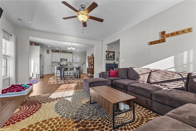 living room featuring wood-type flooring and ceiling fan with notable chandelier