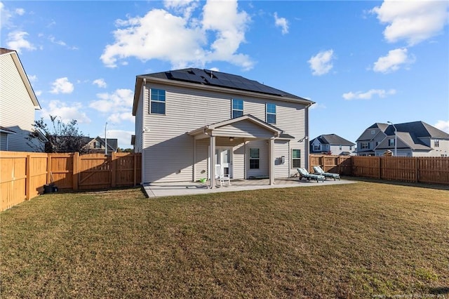 rear view of house with a patio, a yard, and solar panels