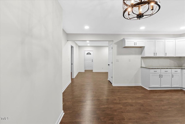 kitchen with light stone countertops, a chandelier, white cabinetry, and dark hardwood / wood-style flooring