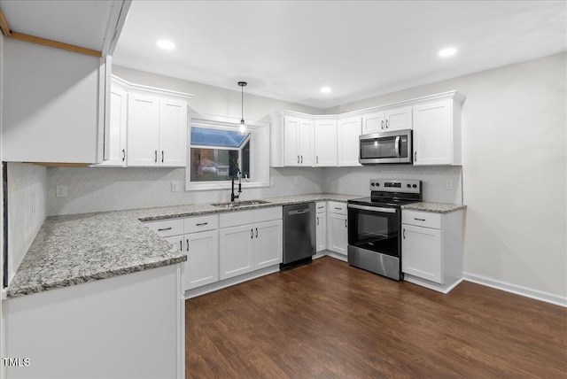 kitchen with dark wood-type flooring, appliances with stainless steel finishes, pendant lighting, and white cabinets