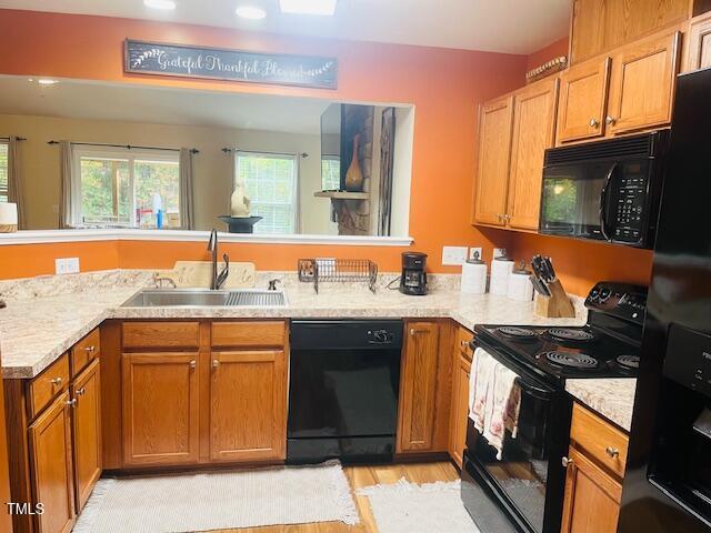 kitchen featuring light hardwood / wood-style floors, black appliances, sink, and kitchen peninsula