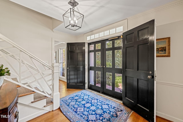 entryway featuring french doors, ornamental molding, a chandelier, and hardwood / wood-style floors