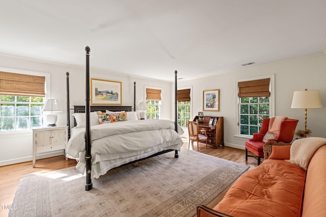 bedroom with crown molding, multiple windows, and light hardwood / wood-style floors