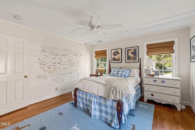 bedroom with multiple windows, wood-type flooring, crown molding, and ceiling fan