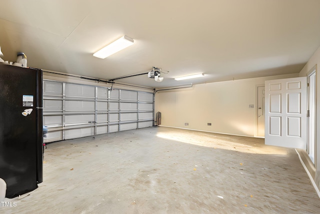 garage featuring a garage door opener and black refrigerator