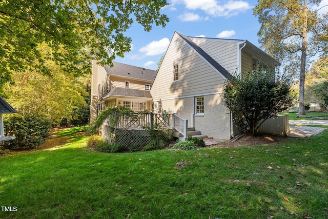 back of property featuring a wooden deck and a yard