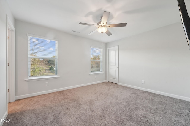 spare room with a wealth of natural light, ceiling fan, and carpet flooring