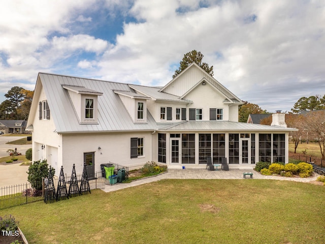 back of house featuring a sunroom, a patio area, and a lawn