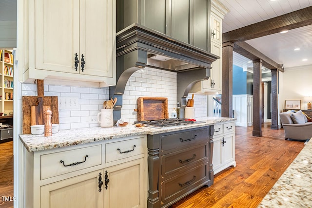 kitchen with beamed ceiling, tasteful backsplash, light stone countertops, and light wood-type flooring