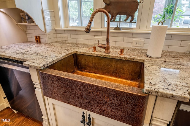 interior details featuring tasteful backsplash, sink, and light stone counters