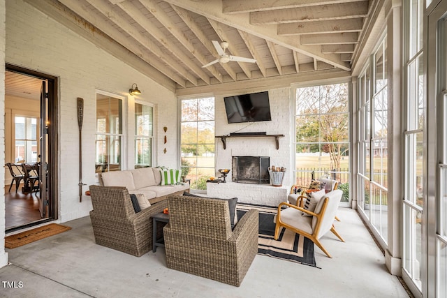 sunroom with an outdoor brick fireplace, vaulted ceiling with beams, a healthy amount of sunlight, and ceiling fan