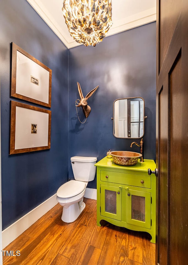 bathroom featuring toilet, an inviting chandelier, ornamental molding, vanity, and hardwood / wood-style flooring