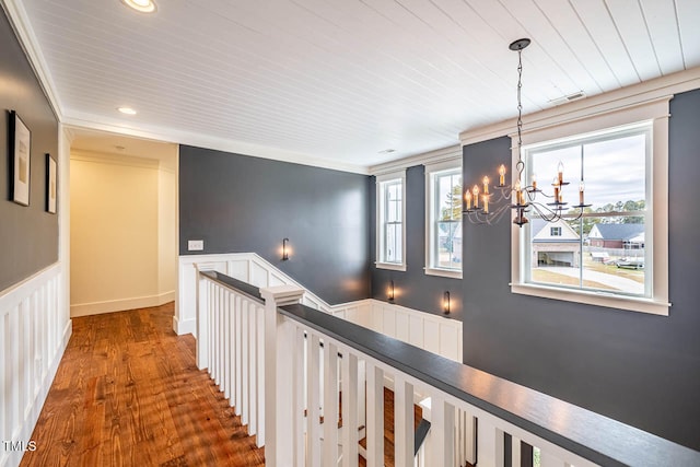 hallway with crown molding, dark hardwood / wood-style flooring, and an inviting chandelier