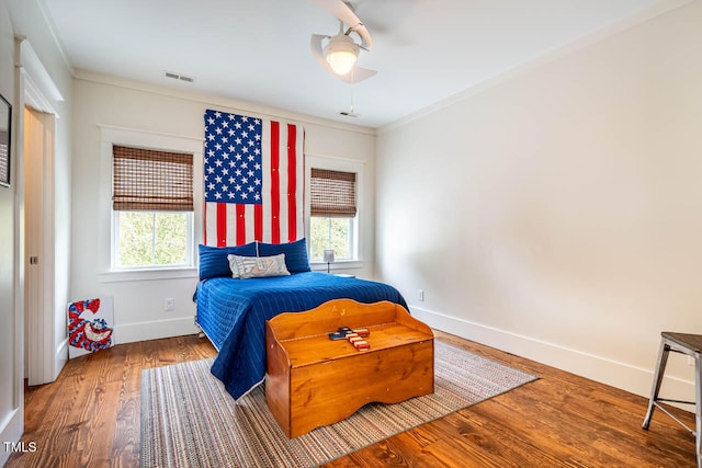 bedroom with multiple windows, crown molding, ceiling fan, and hardwood / wood-style flooring