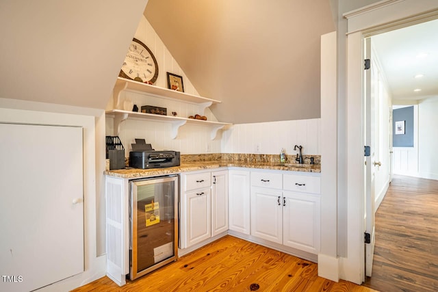 kitchen featuring wine cooler, sink, light hardwood / wood-style flooring, and white cabinets