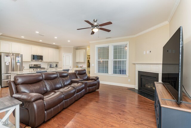 living room with ceiling fan, ornamental molding, and light wood-type flooring