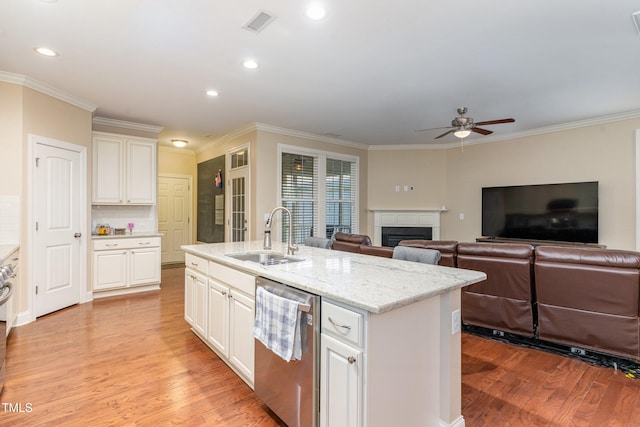 kitchen featuring a kitchen island with sink, dishwasher, light hardwood / wood-style floors, crown molding, and sink