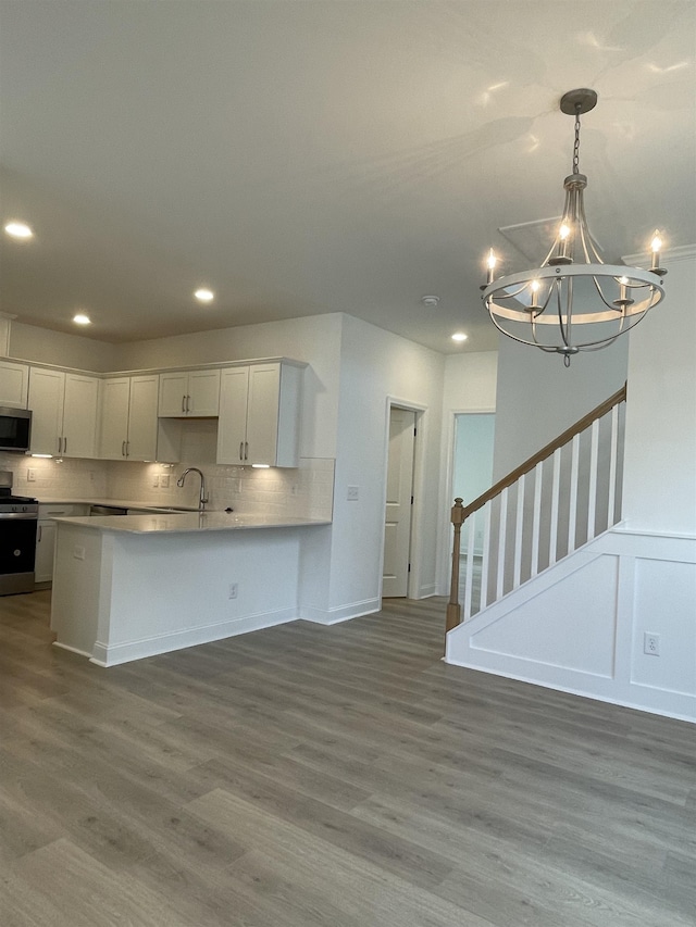 kitchen featuring white cabinets, appliances with stainless steel finishes, hardwood / wood-style flooring, and hanging light fixtures