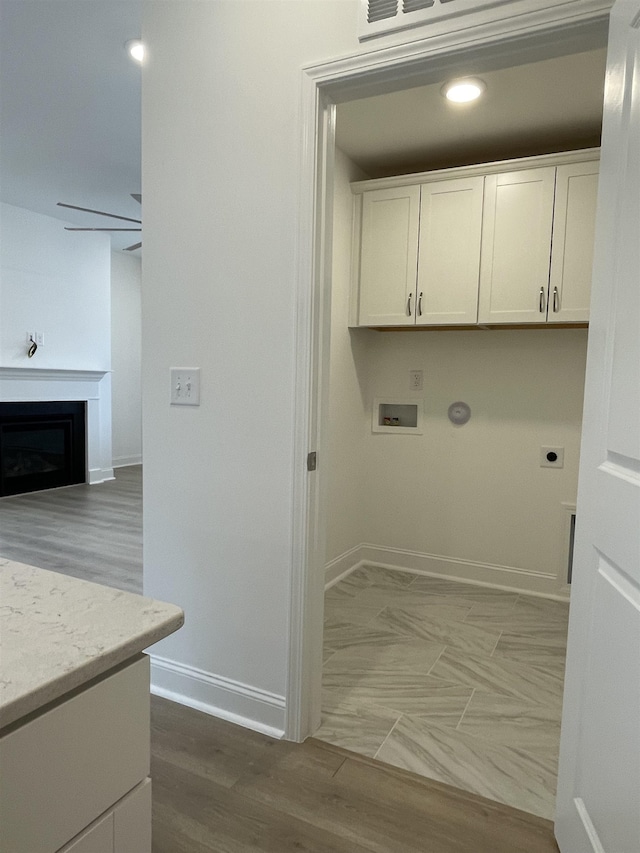 clothes washing area with ceiling fan, washer hookup, cabinets, hookup for an electric dryer, and hardwood / wood-style flooring