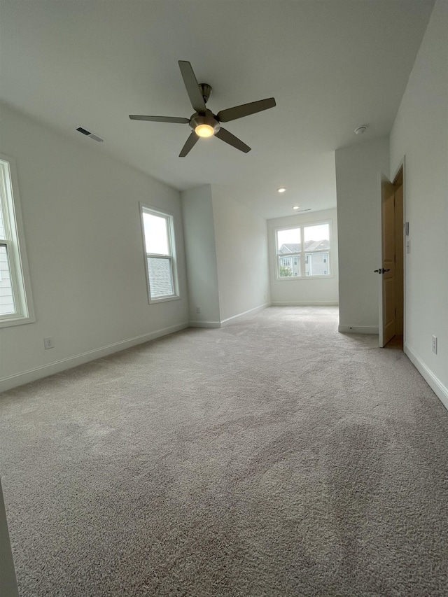 empty room featuring light carpet, plenty of natural light, and ceiling fan