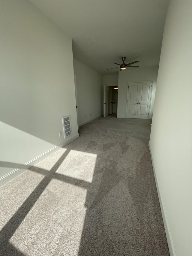 unfurnished living room featuring carpet floors and ceiling fan