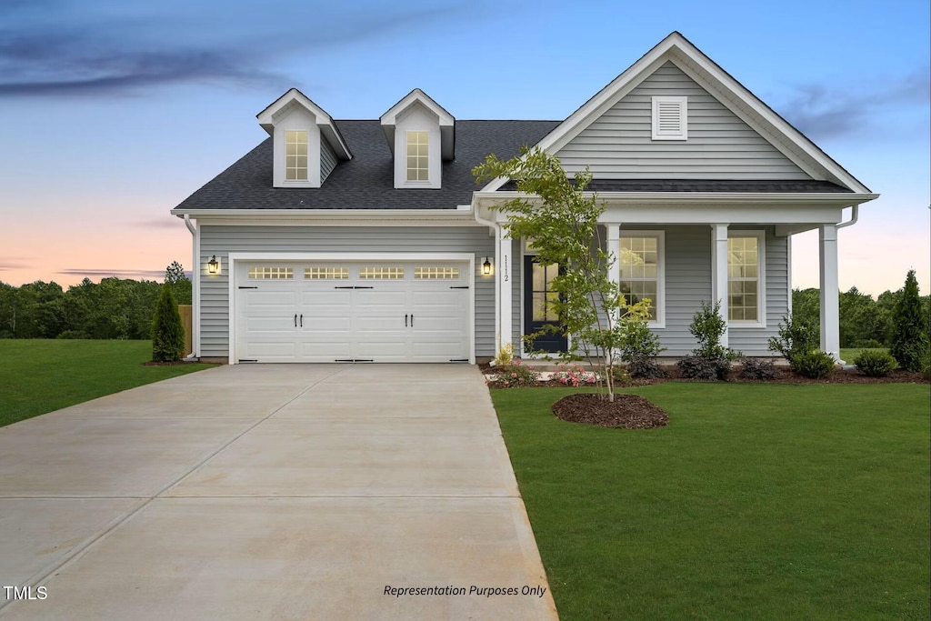 view of front of property with a yard, a porch, and a garage