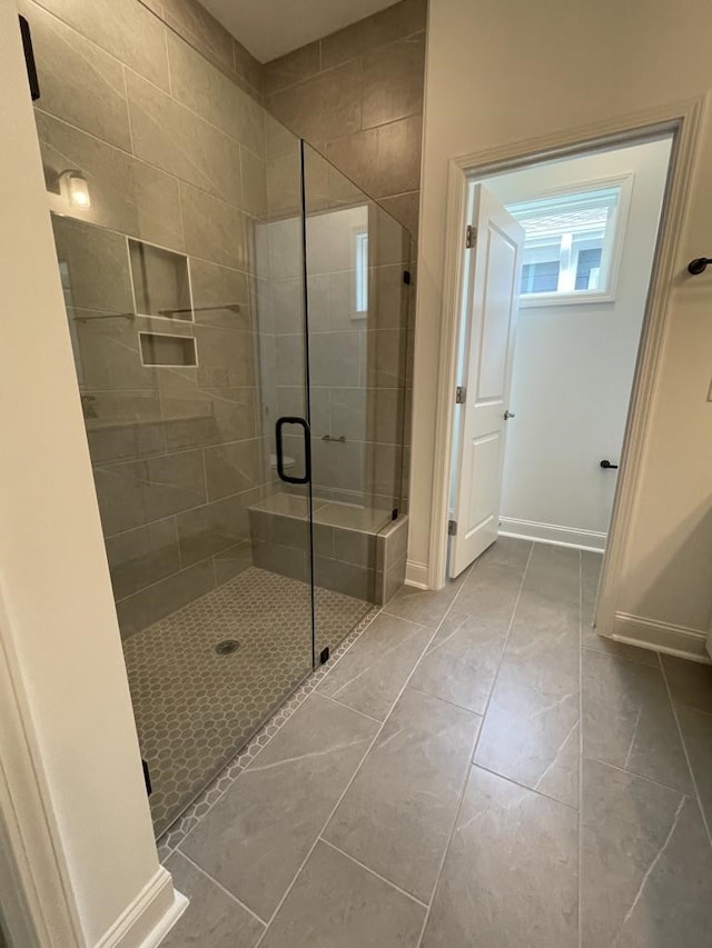 bathroom with a shower with door and tile patterned floors