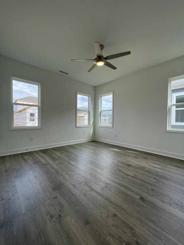 unfurnished room featuring ceiling fan, a wealth of natural light, and dark hardwood / wood-style floors