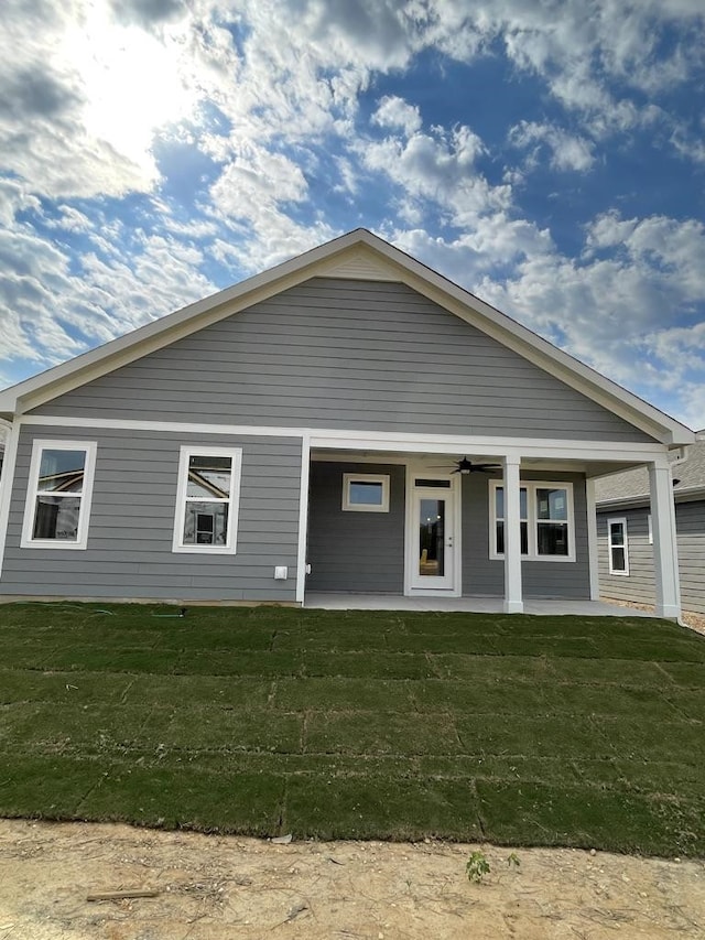 rear view of house with a yard and ceiling fan